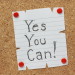 The phrase Yes You Can on a cork notice board