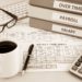 Human resources documents: payroll, salary and employee  time sheets place on office table with cup of coffee and calculator, sepia tone
