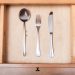 above view of table knife, fork, spoon in open drawer of nightstand